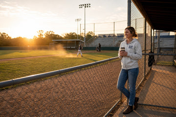 Vintage-inspired sports mom watching her child play during a youth baseball game on a sunny afternoon.